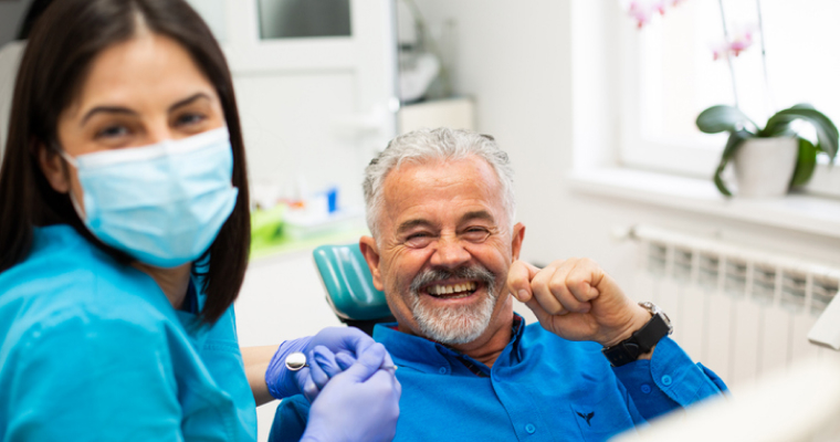 Happy man in a dentist’s chair beside a dental hygienist